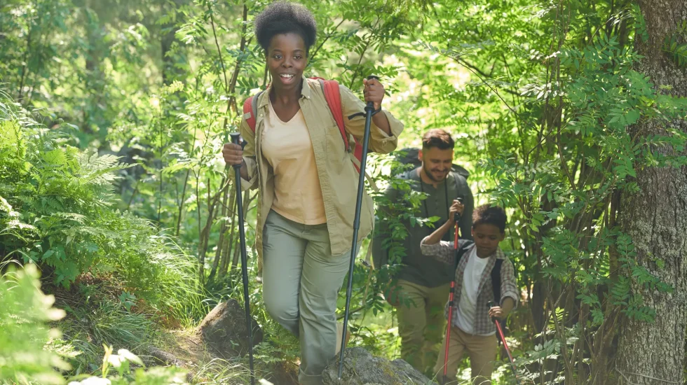 african-young-woman-with-backpack-walking-with-sticks-she-go-hiking-forest-together-with-her-family